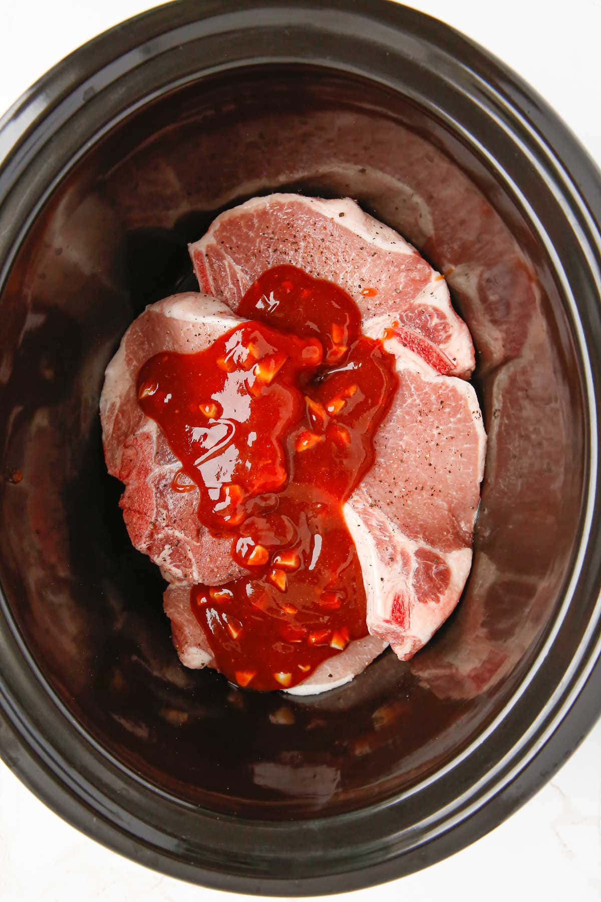 Pork chops in the slow cooker covered with sauce.