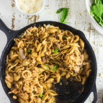 Overhead view of an iron skillet full of casserole with a text overlay for Pinterest.