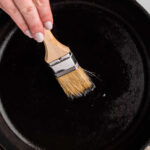 A person seasoning a cast iron skillet with text overlay for pinterest.