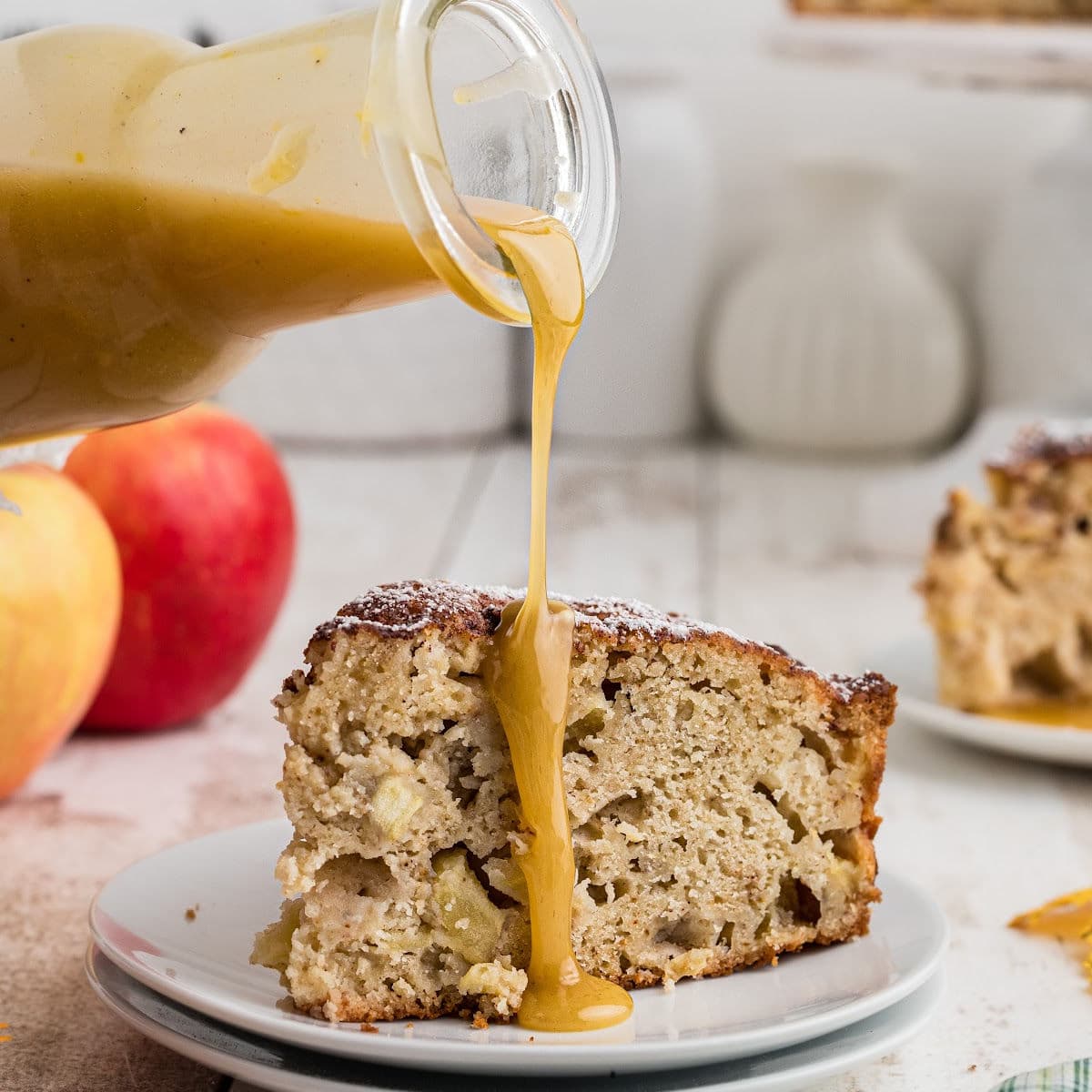 Closeup of whiskey brown butter sauce being poured over a slice of apple cake.