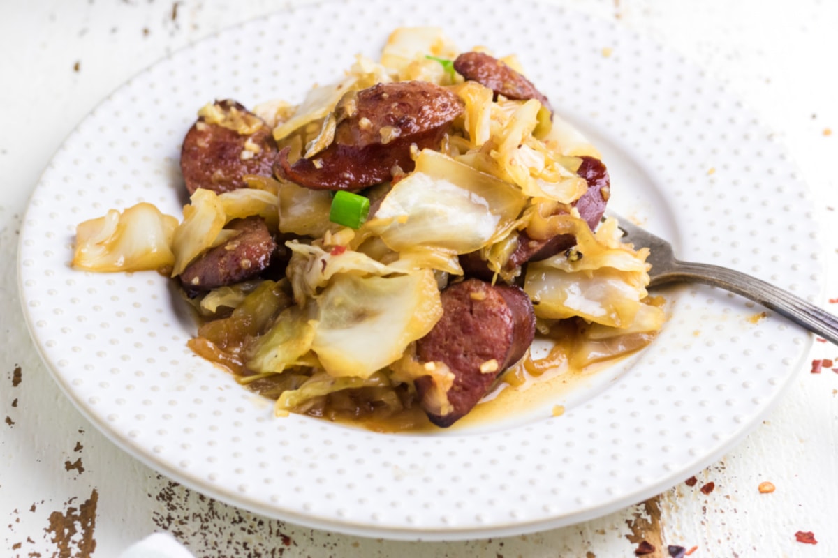 Closeup of a serving of kielbasa and cabbage on a white plage.