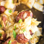 Closeup of the pan of kielbasa and cabbage with text overlay for Pinterest.