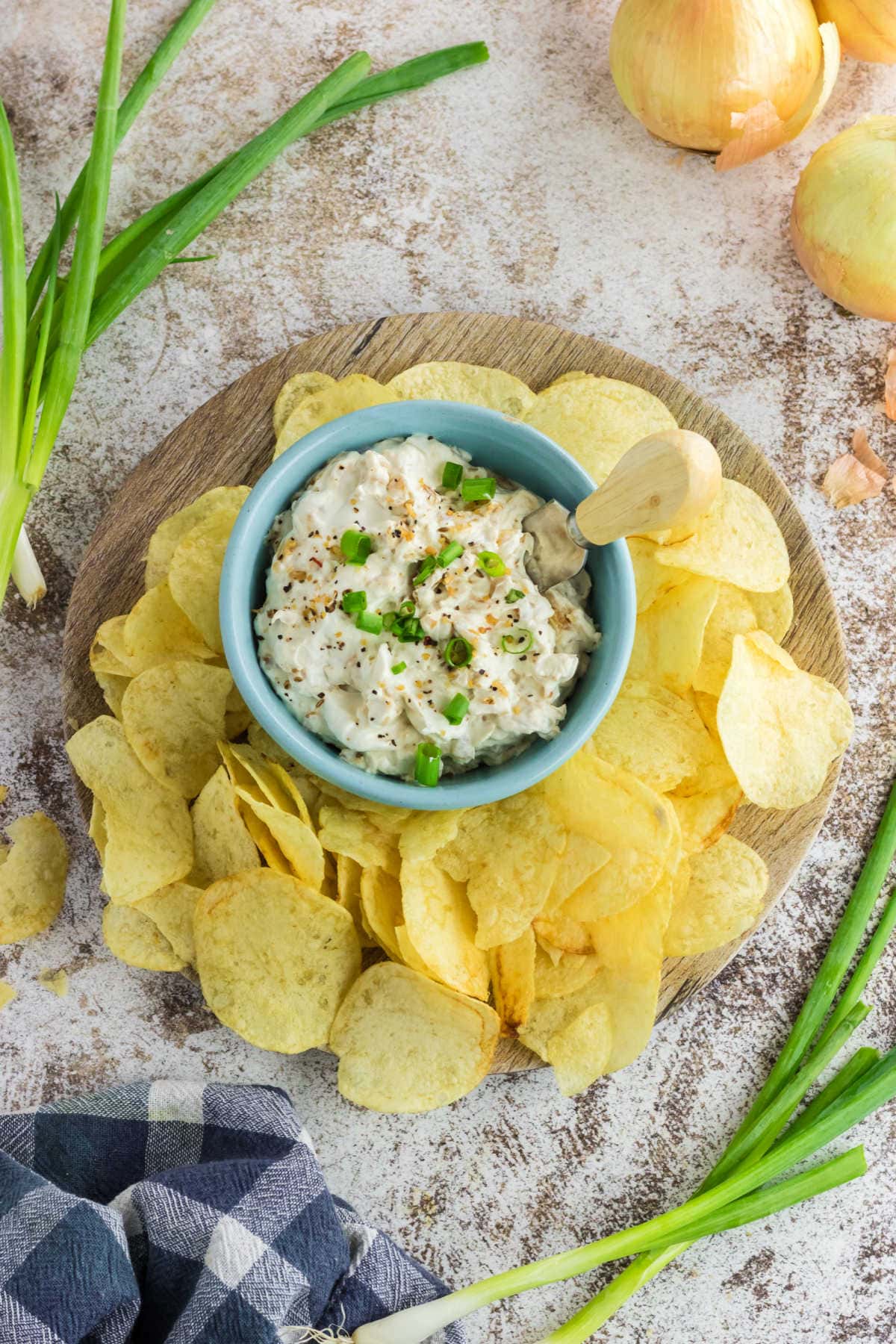 A bowl of onion dip surrounded by potato chips.