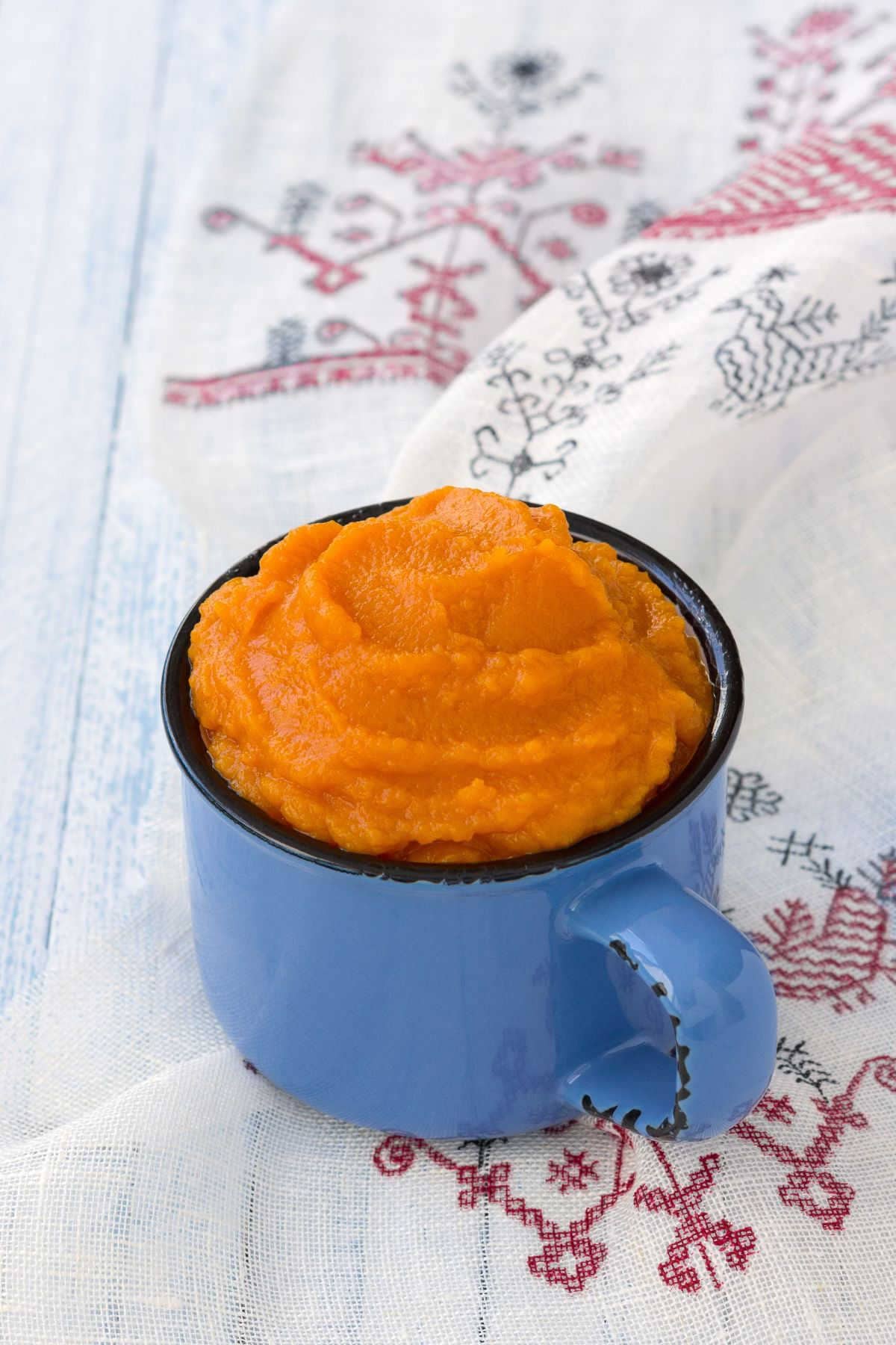 A blue cup with pumpkin puree in it.