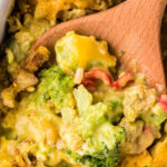 A wooden spoon spooning up a broccoli and cheese casserole with text overlay for pinterest.