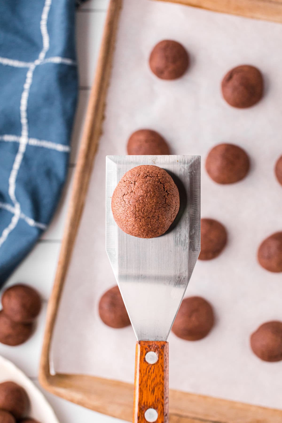 A baked chocolate butter cookie being lifted from the cookie sheet.