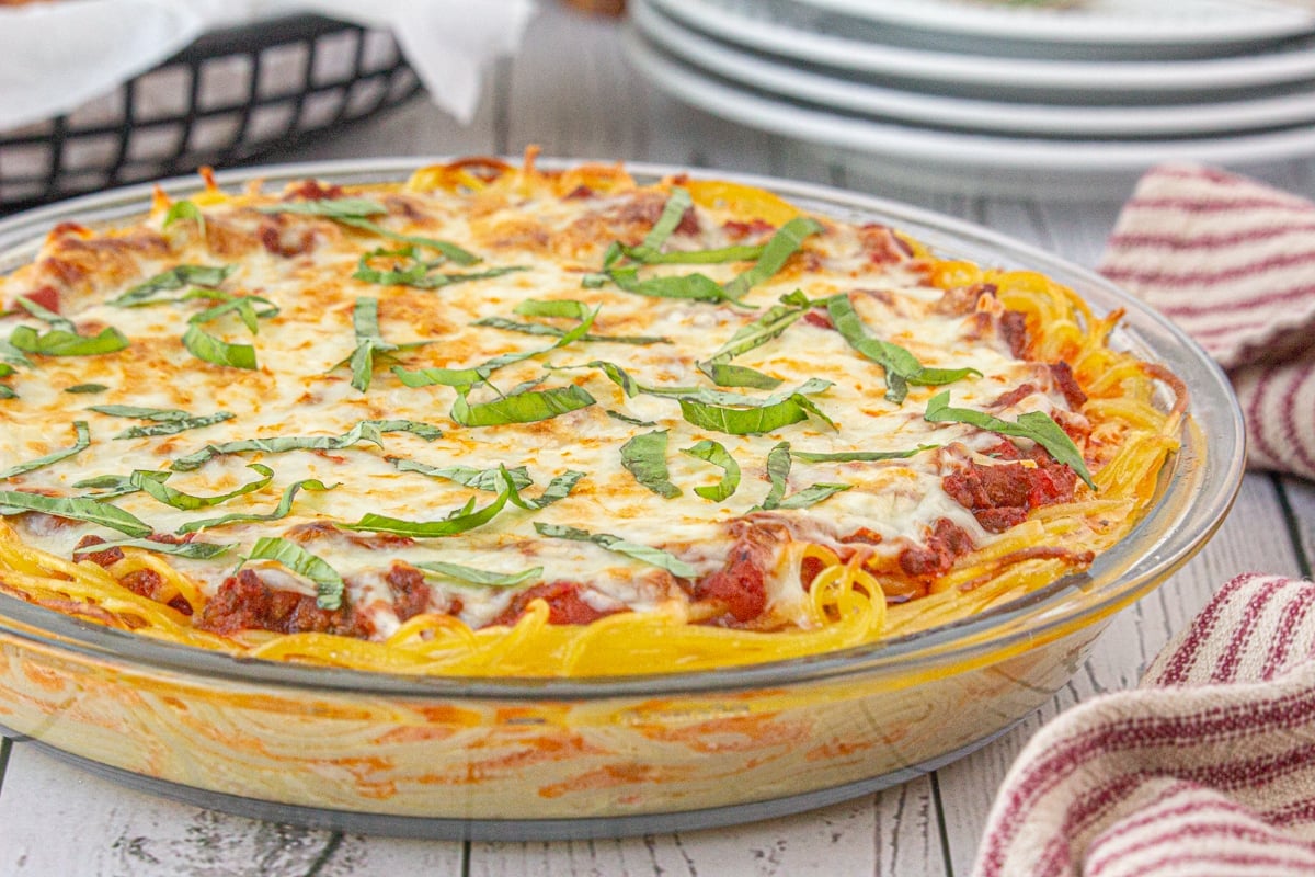 A whole spaghetti pie in a pie pan cooling on a table.