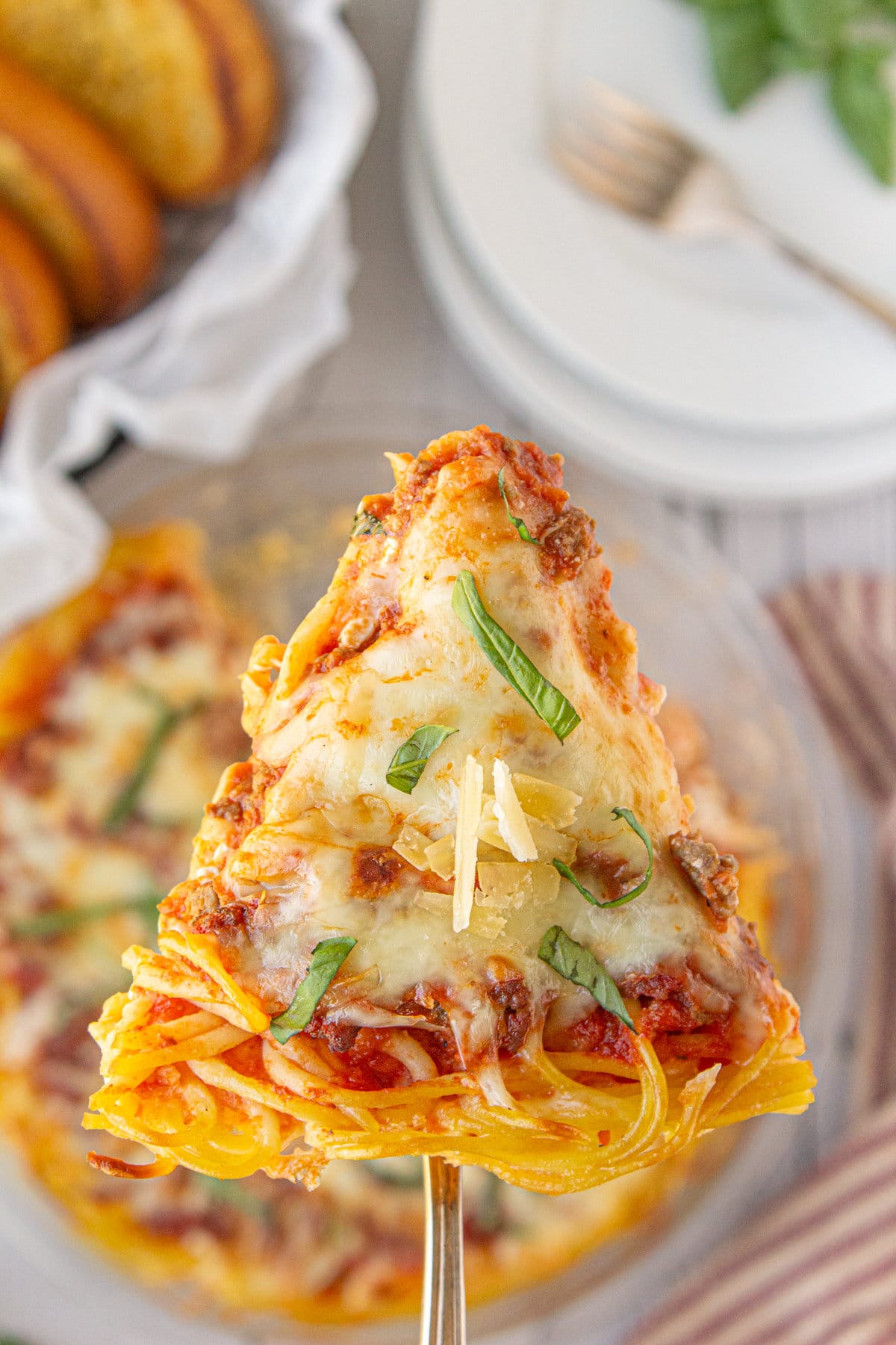 Overhead view of a wedge of cheesy spaghetti pie being served.