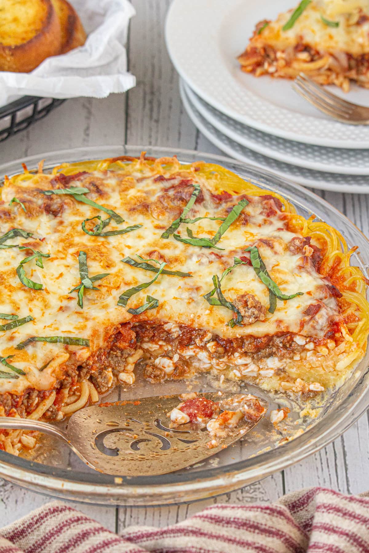 Spaghetti pie made with cottage cheese in a pie dish with a slice removed.
