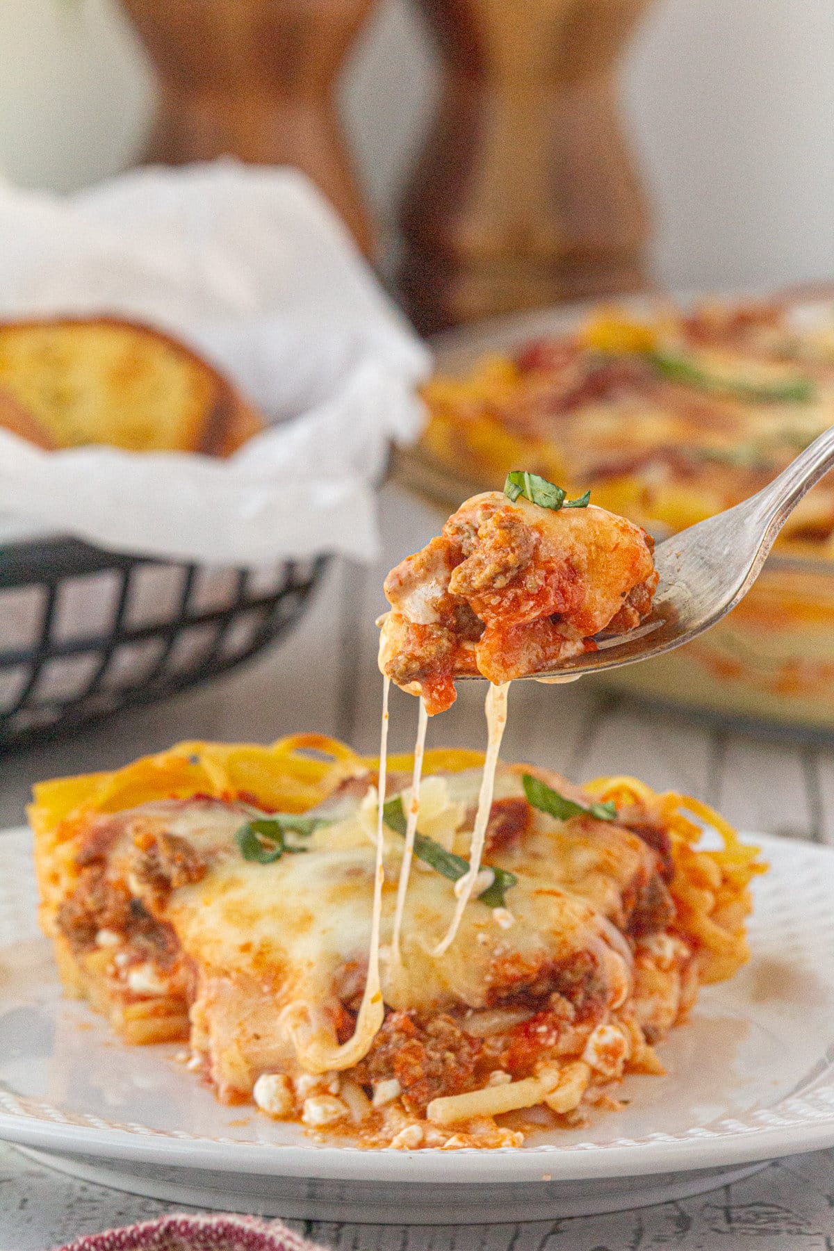 Homemade spaghetti pie on a plate with a fork pulling up a cheesy bite.