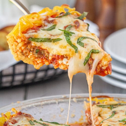 Slice of homemade spaghetti pie with cheese dripping from it.