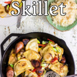 An iron skillet full of kielbasa and pierogi with a text overlay for Pinterest.