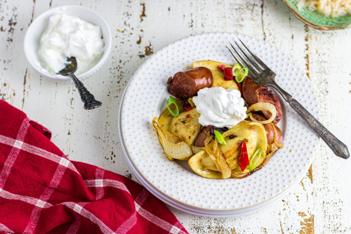 A plate of pierogi and kielbasa on a table.