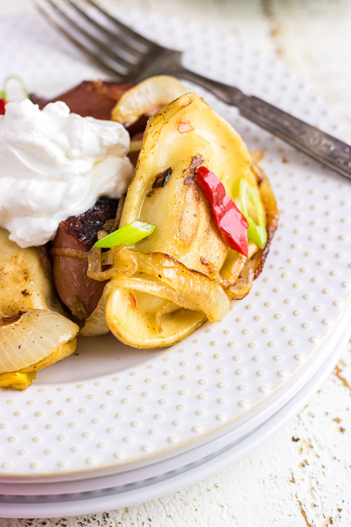 Closeup of a plate of pierogi and kielbasa.