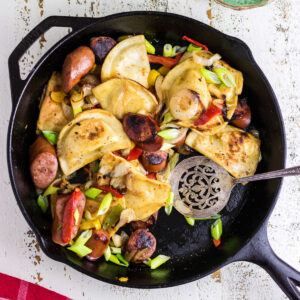 Overhead view of a skillet of pierogi and kielbasa that's ready to eat.