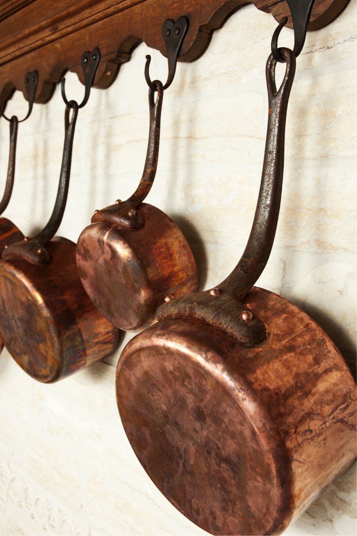 Copper saucepans hanging on hooks.