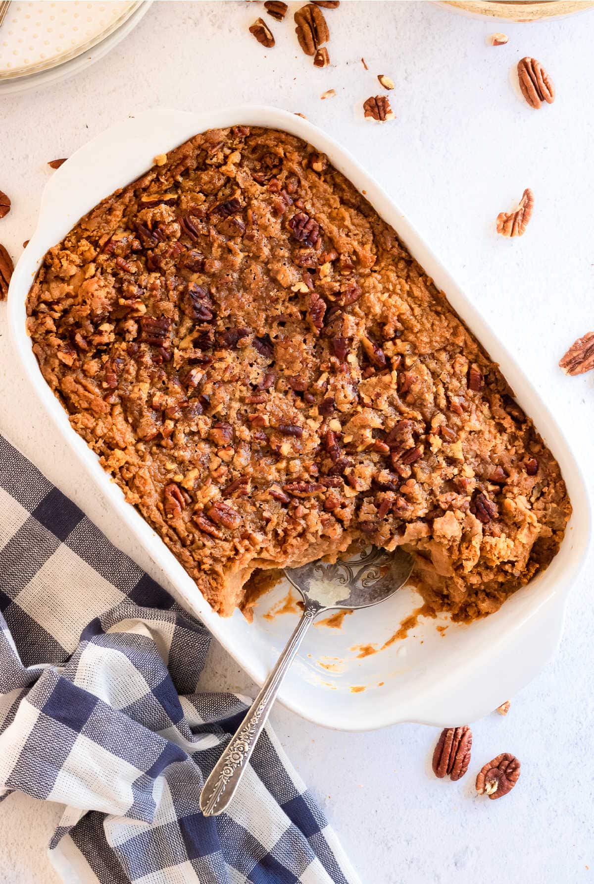 Overhead view of bourbon sweet potato casserole in a white casserole dish. The top is covered with toasted pecans.