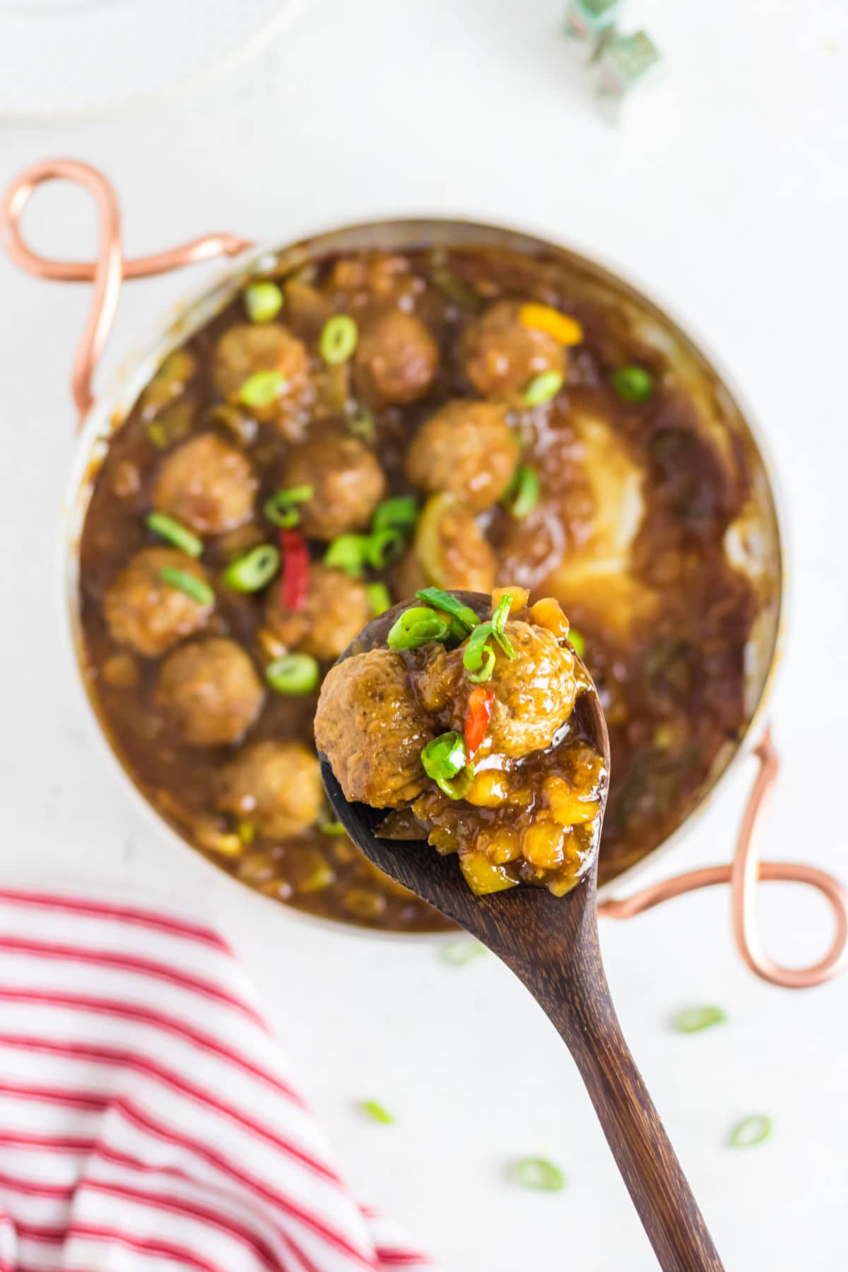 Finished meatballs being served with a wooden spoon.