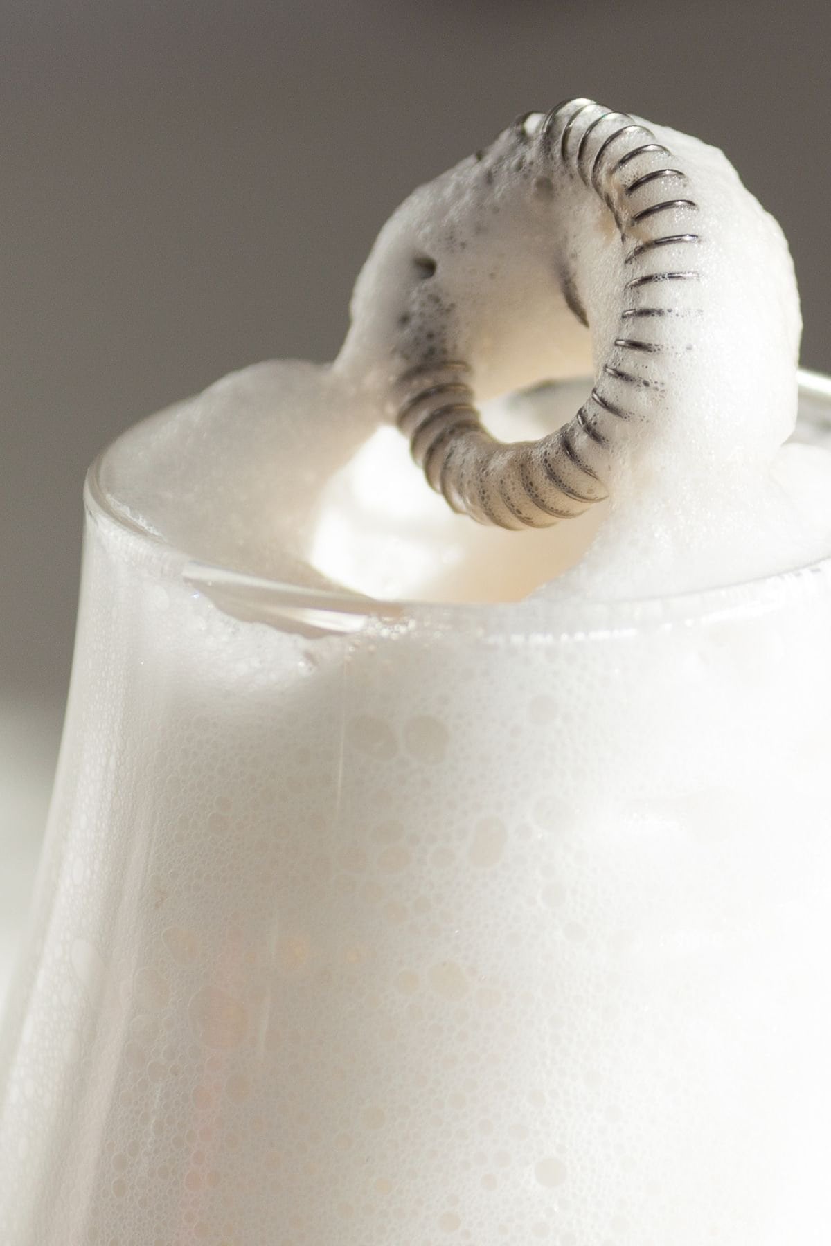 Closeup of a milk frother with thick milk foam on it.
