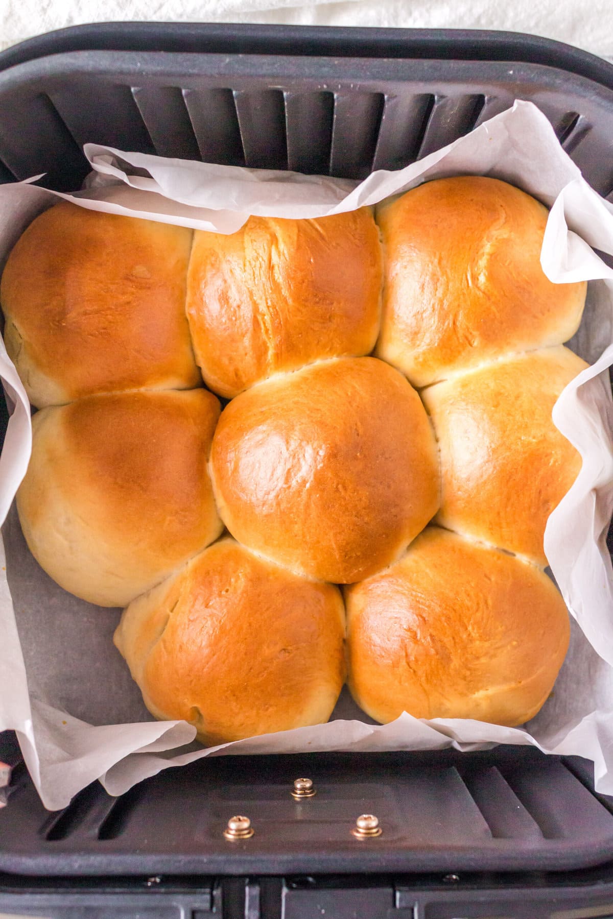 Golden brown rolls in the air fryer basket after baking.