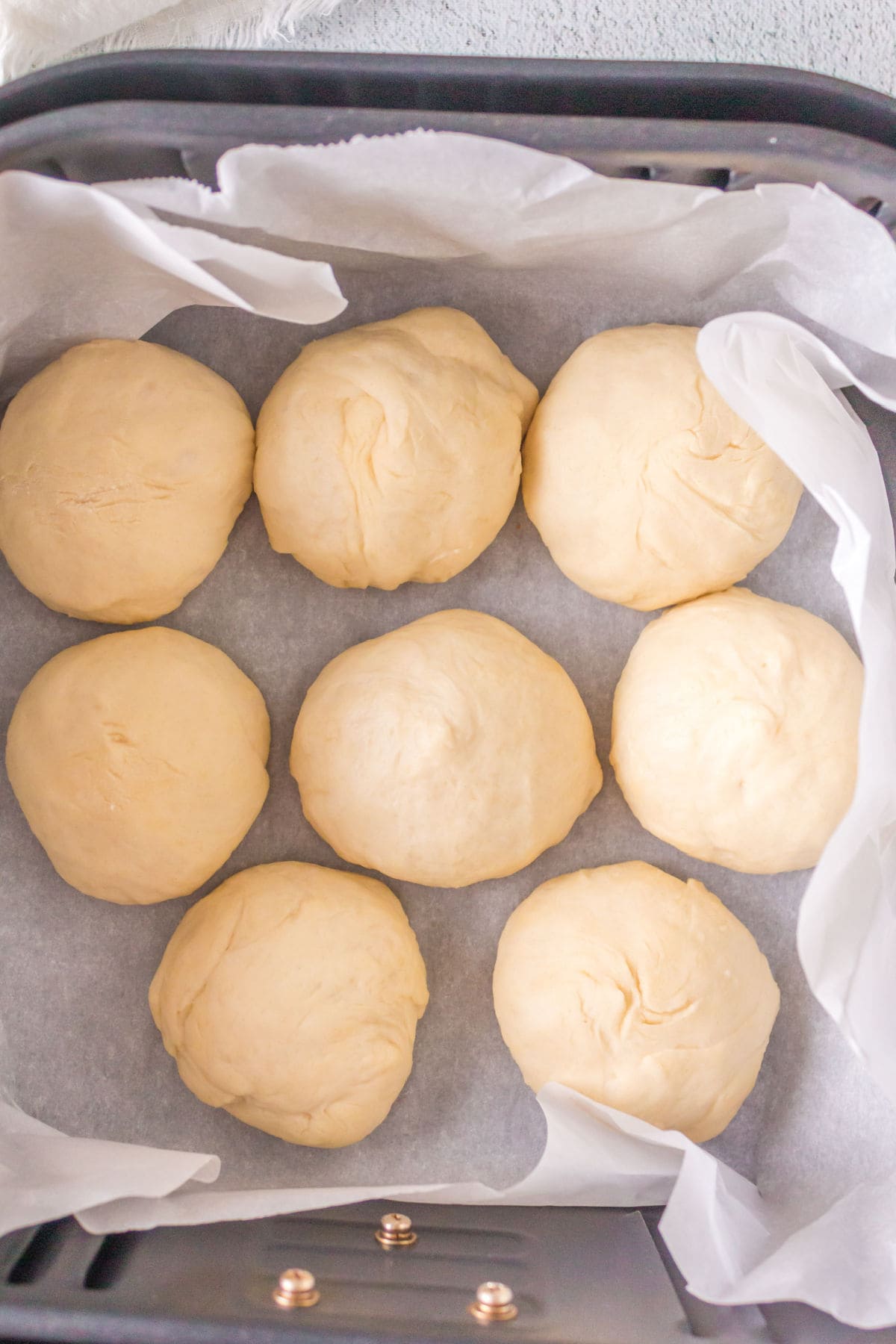 RIsen rolls in the air fryer basket ready to be baked.