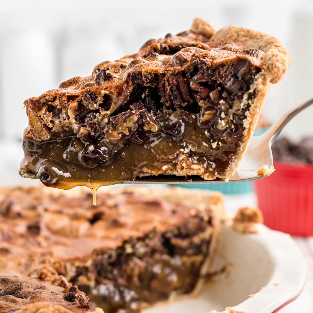 A slice of chocolate bourbon pecan pie being removed from the pie dish.