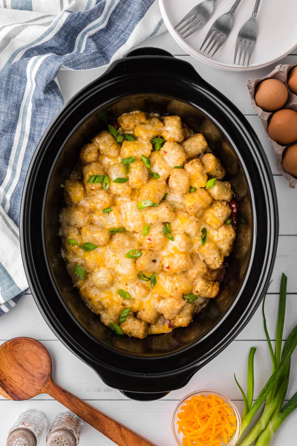 Cheesy tater tot casserole in a crockpot, topped with green onions. 