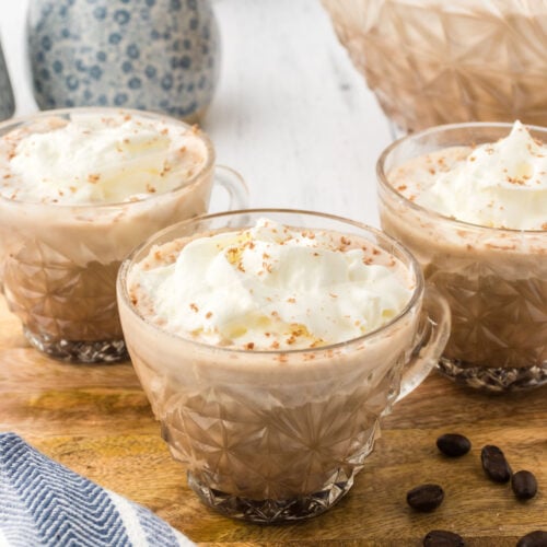 Three cups full of coffee punch with whipped cream on top.