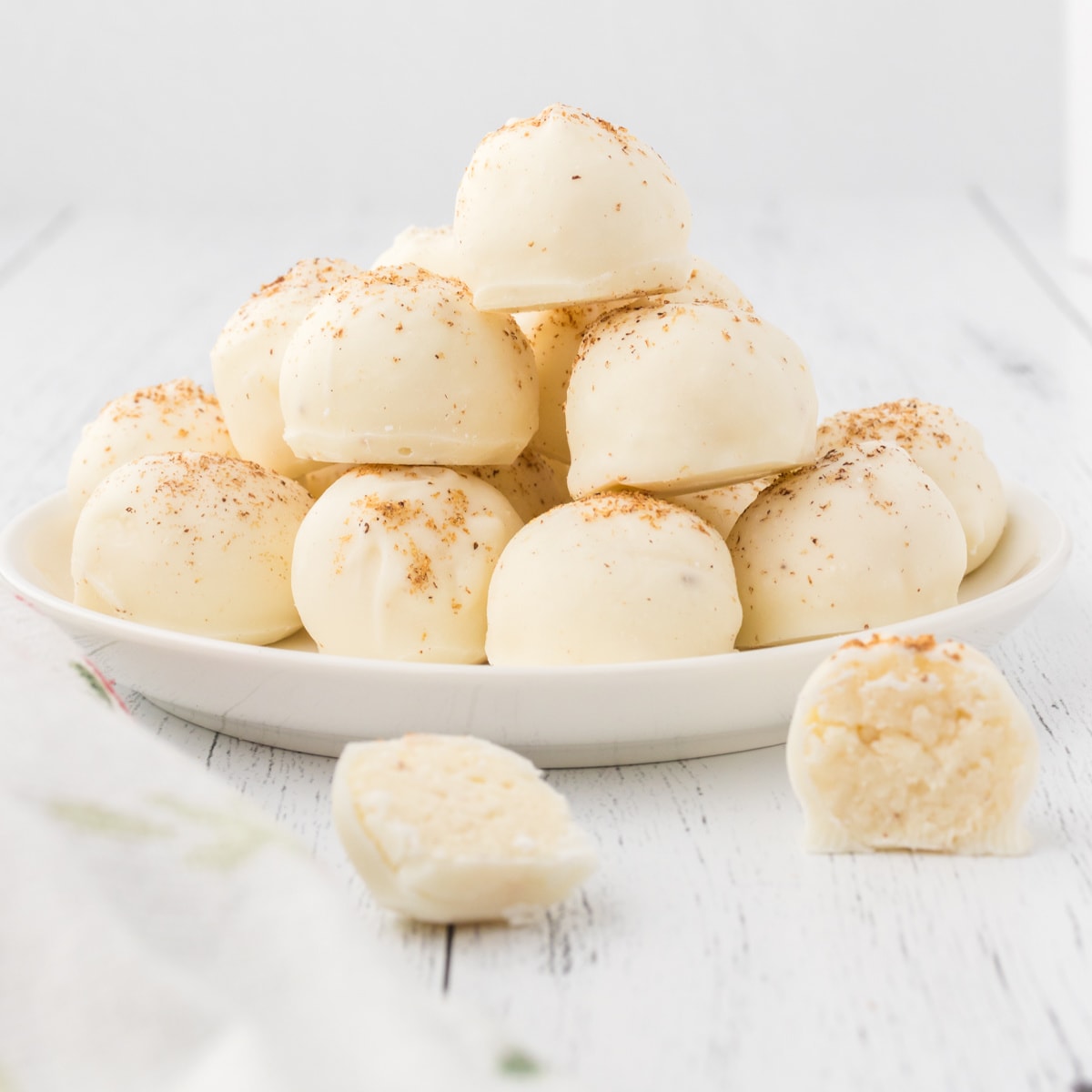 Homemade egg nog truffles on a white plate.