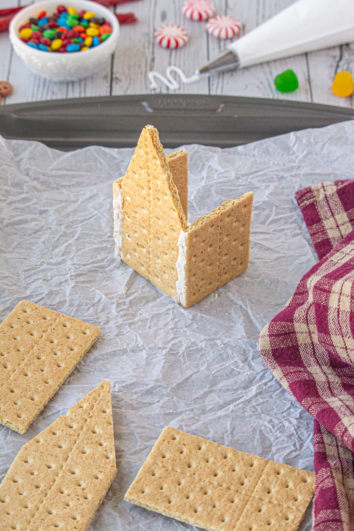 Spread beads of icing on either side of the other pointed graham cracker. Gently push it onto the open end of the house.