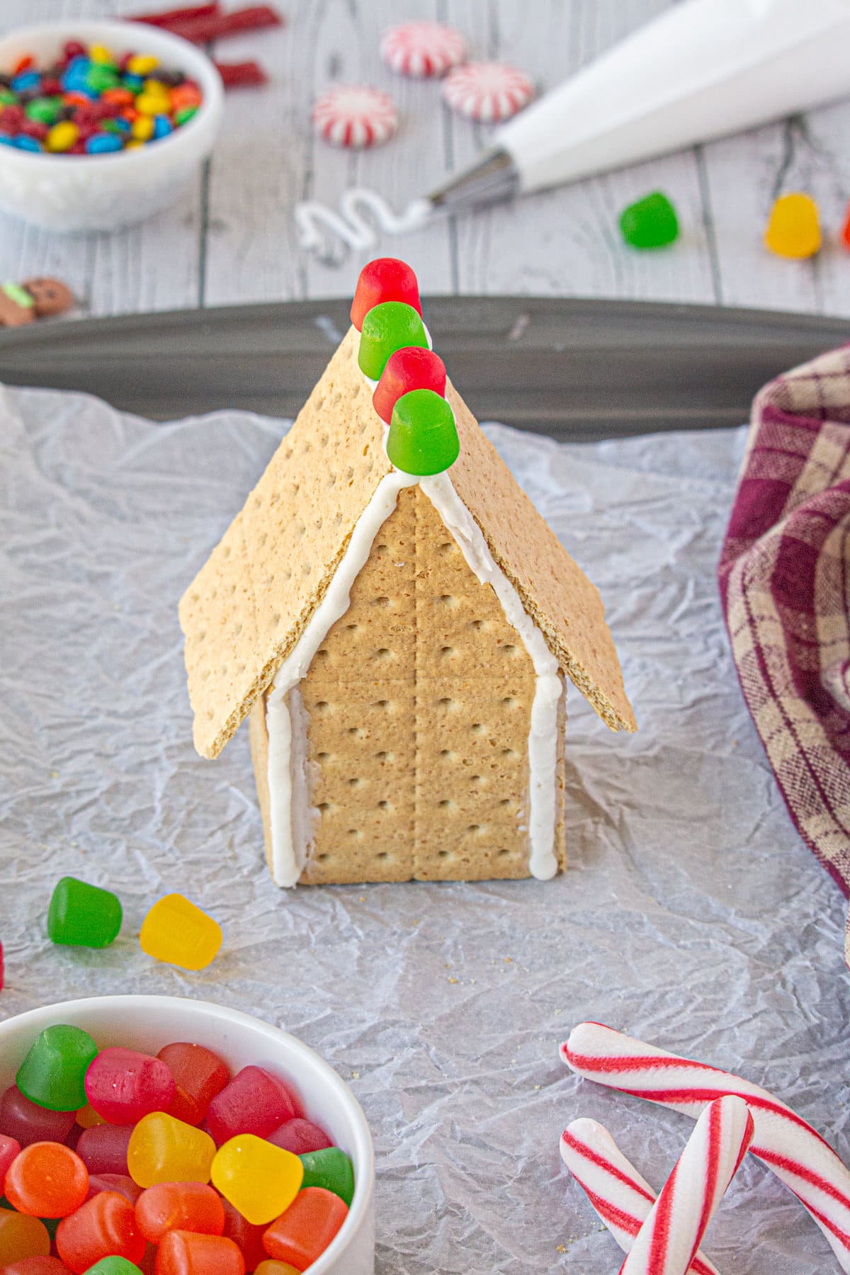 A finished gingerbread house with the roof being decorated.