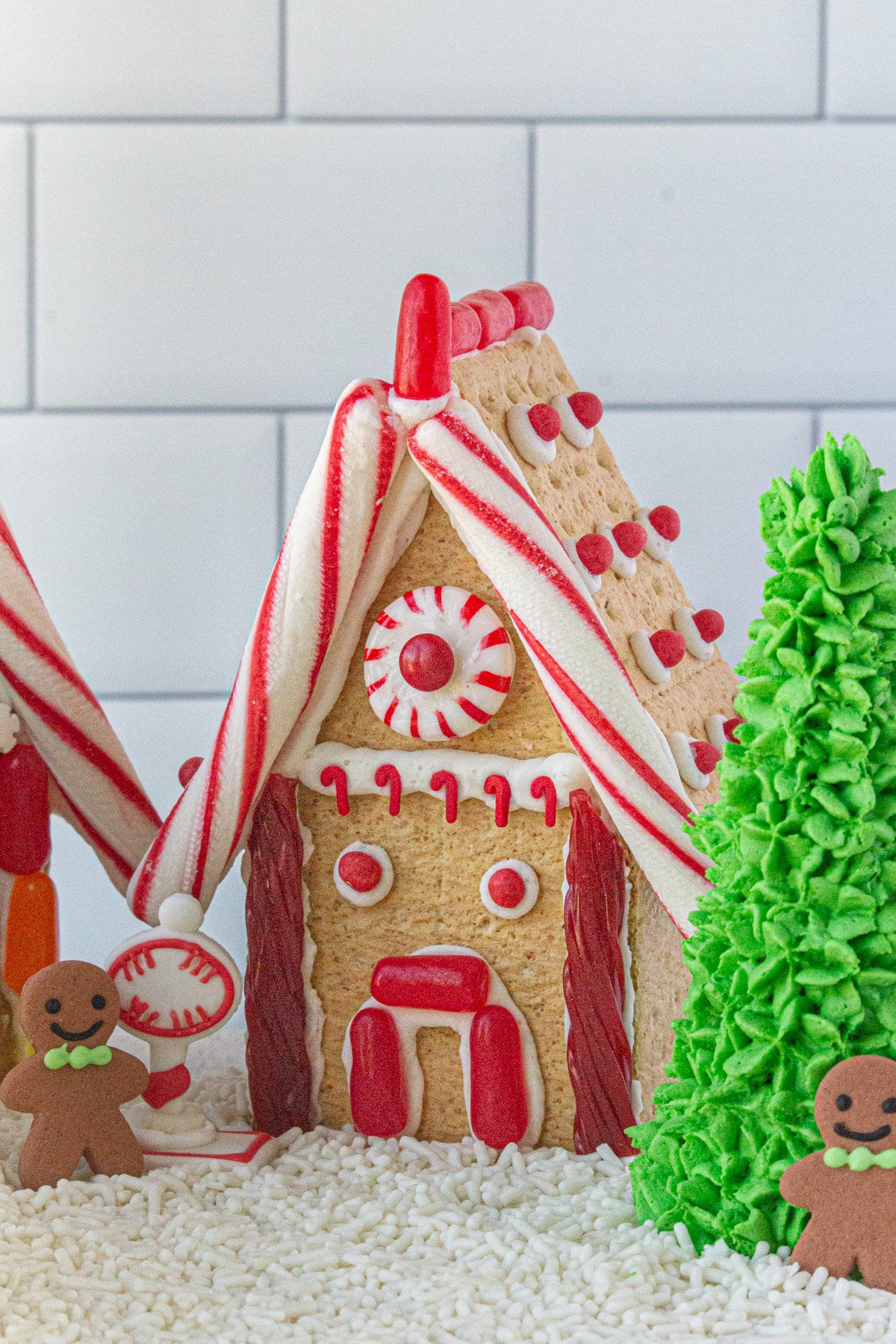 A finished gingerbread house decorated with red licorice.