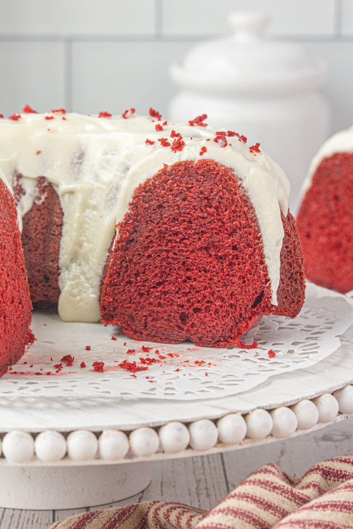 Red velvet bundt cake with cream cheese glaze on a cake stand.