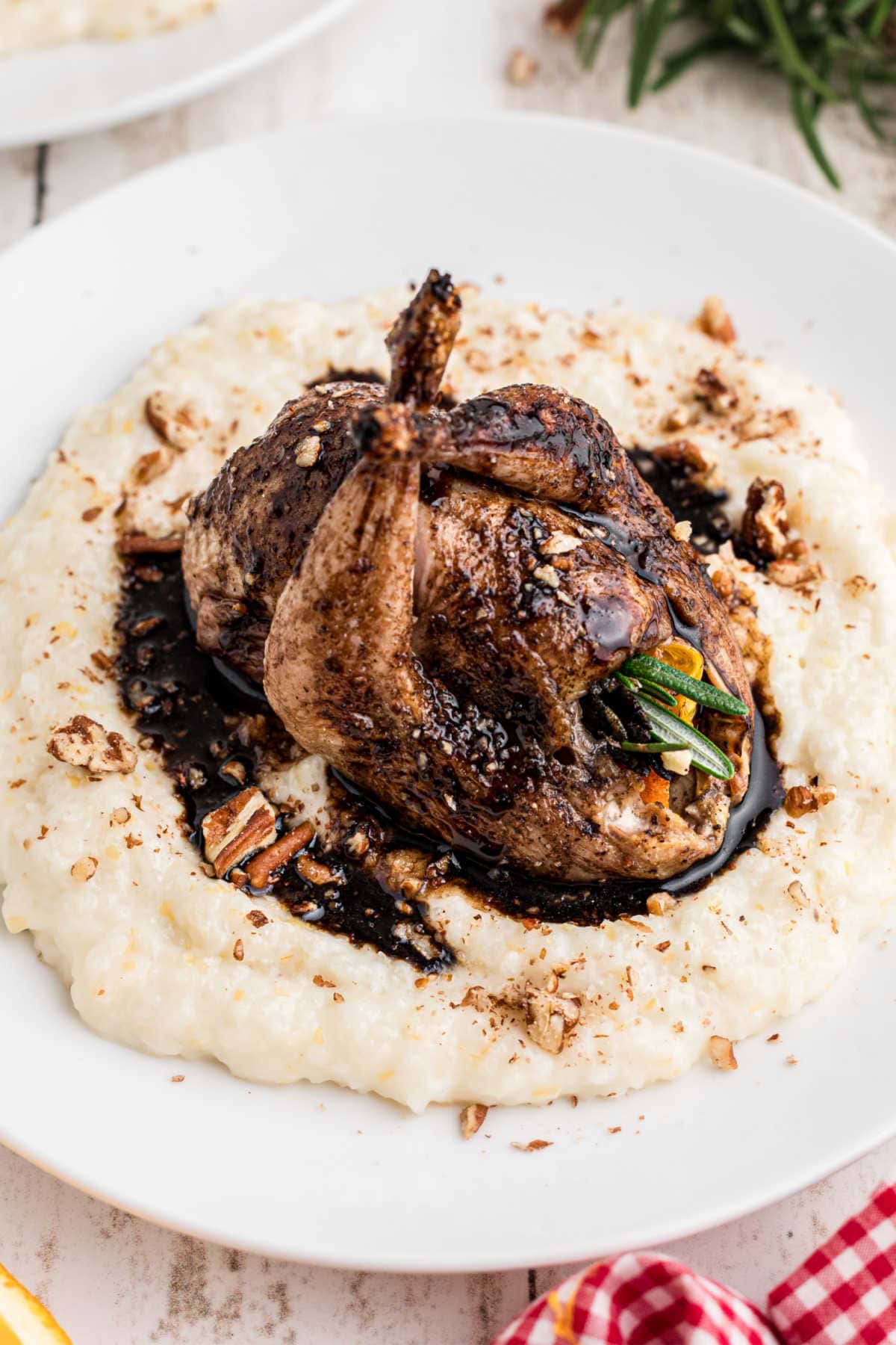 A roasted quail on a bed of cheese grits.