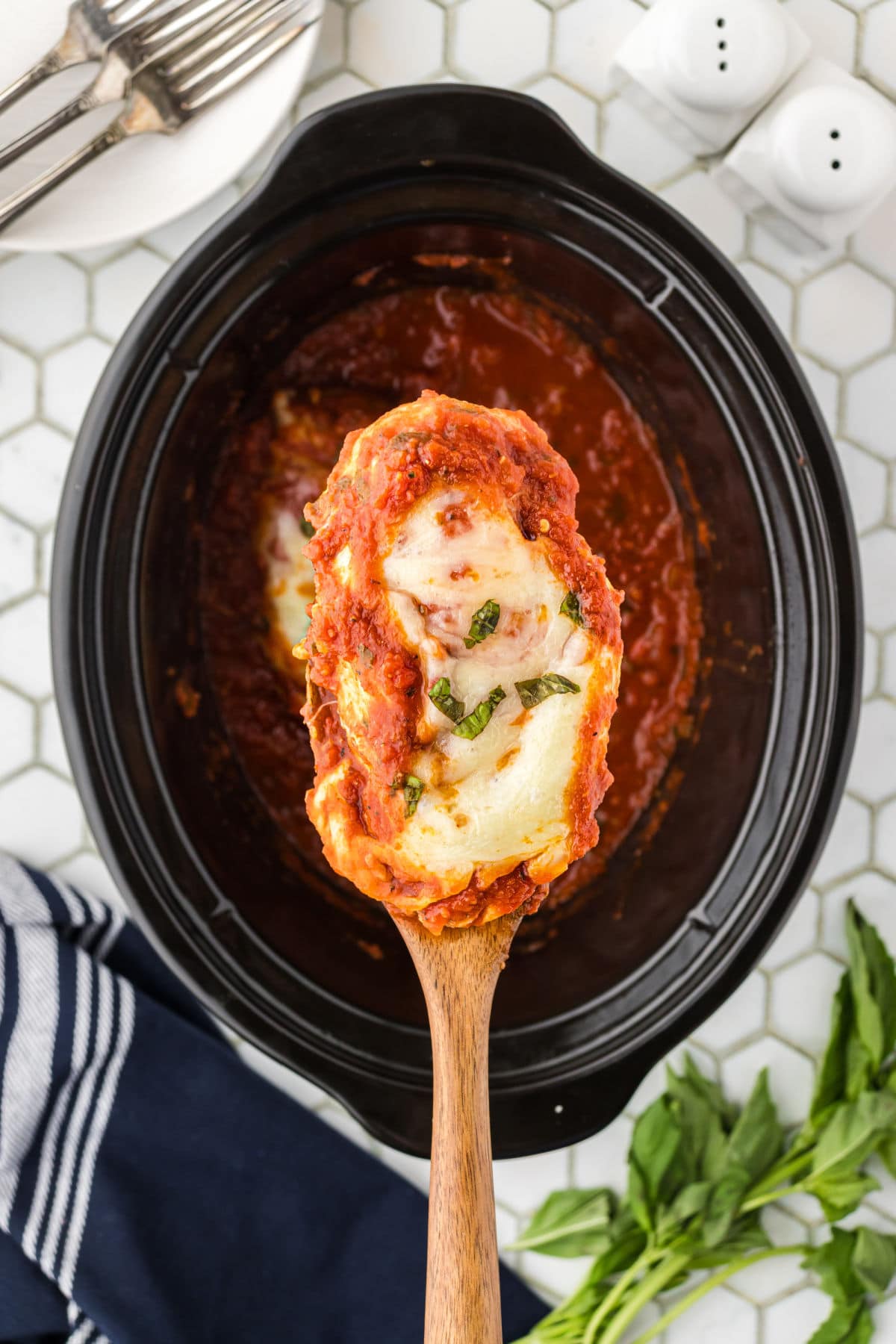 A serving of chicken parmesan being removed from the slow cooker.