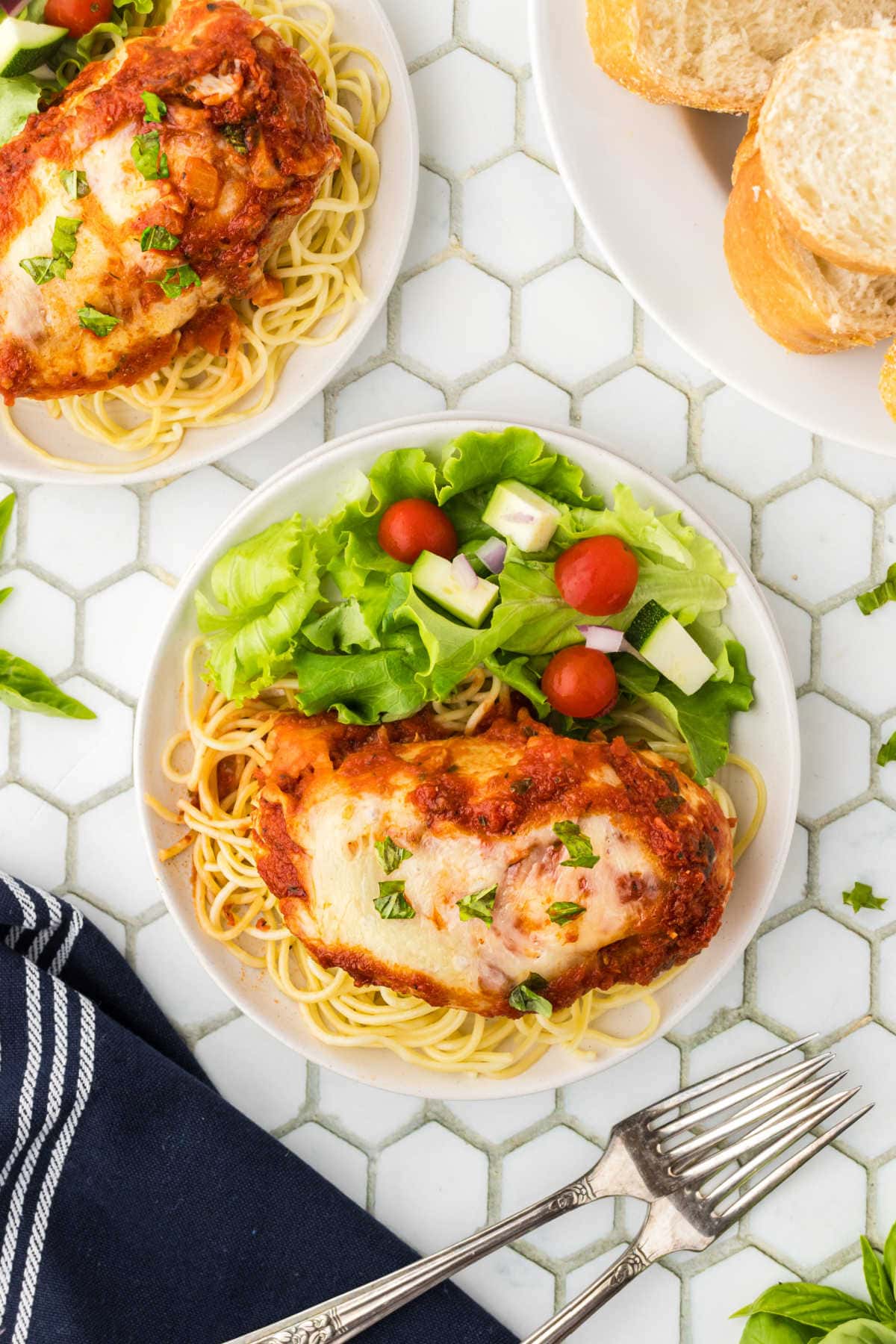 Chicken parmesan on a plate with pasta and salad.