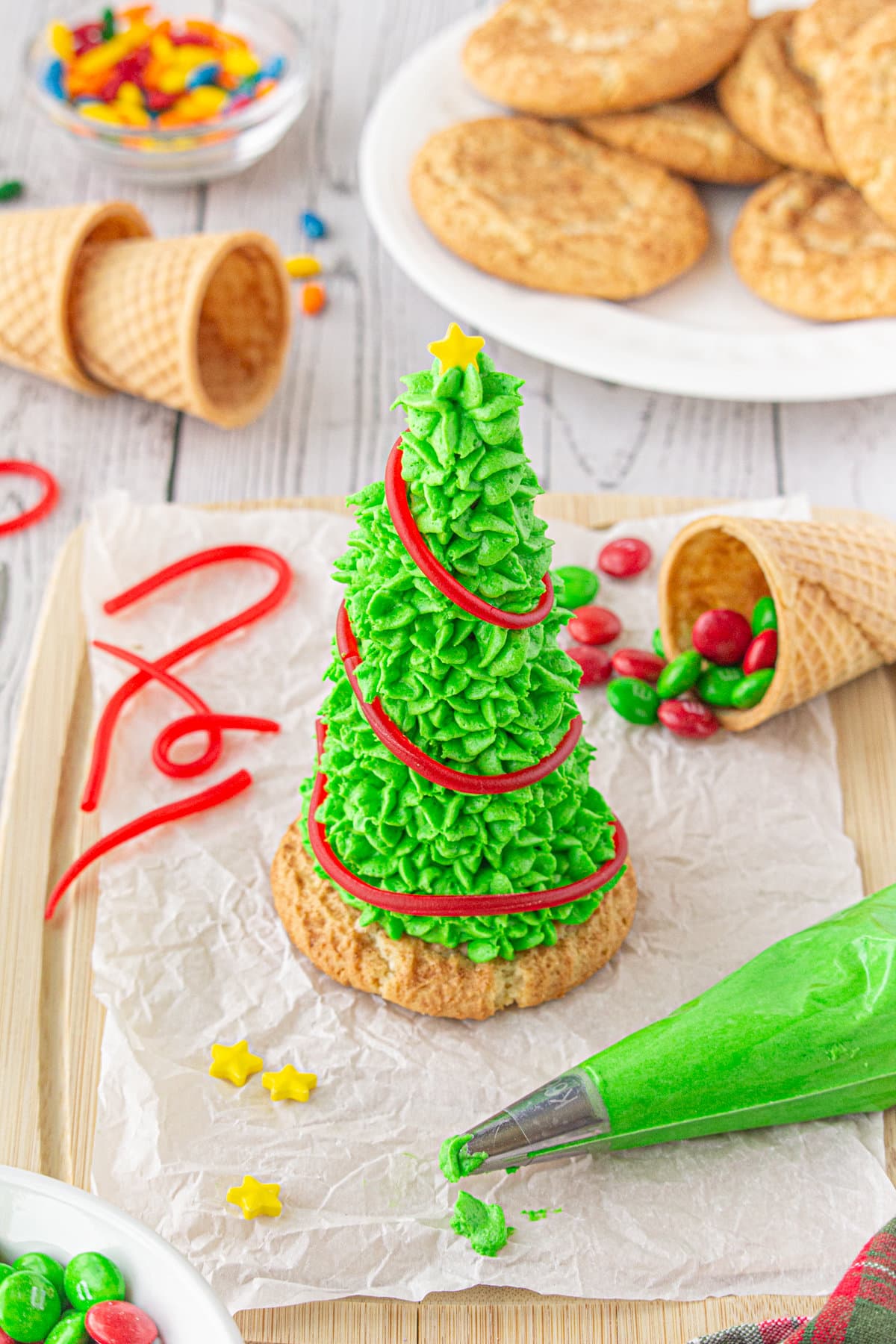 A sugar cone Christmas tree being decorated with candy ornaments.