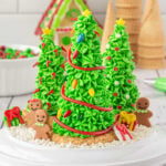 A plate with 3 decorated sugar cone Christmas trees on it.