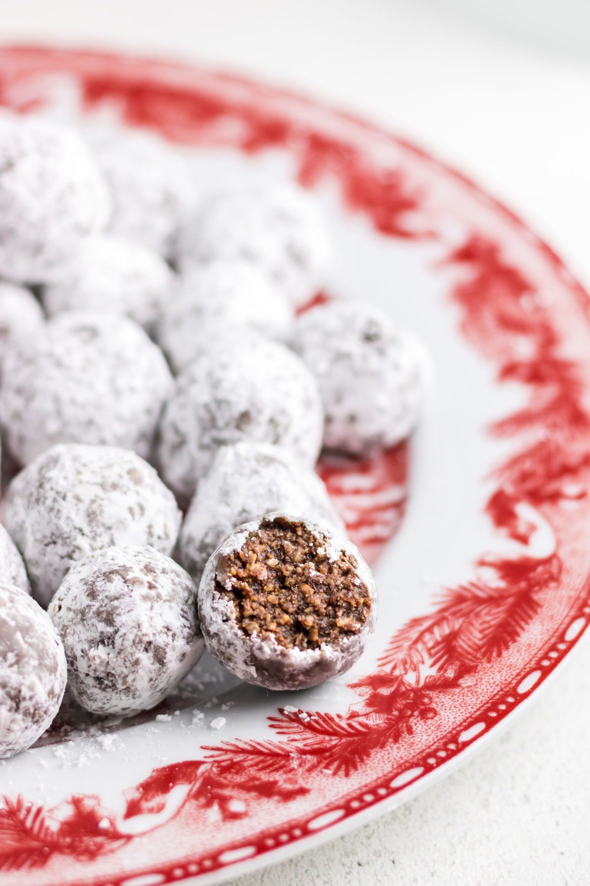 Closeup of bourbon balls covered in white powdered sugar on a red plate.