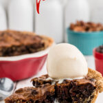 A slice of chocolate bourbon pecan pie with a scoop of ice cream melting on top.