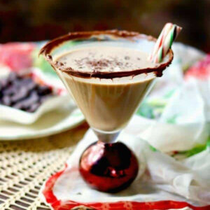 Closeup of a chocolate drink in a martini glass with a peppermint garnish.