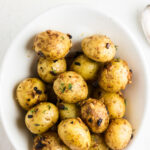 Overhead view of roasted potatoes in a white bowl with a title text overlay for Pinterest.