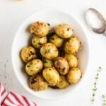 Roasted baby potatoes in a white bowl.