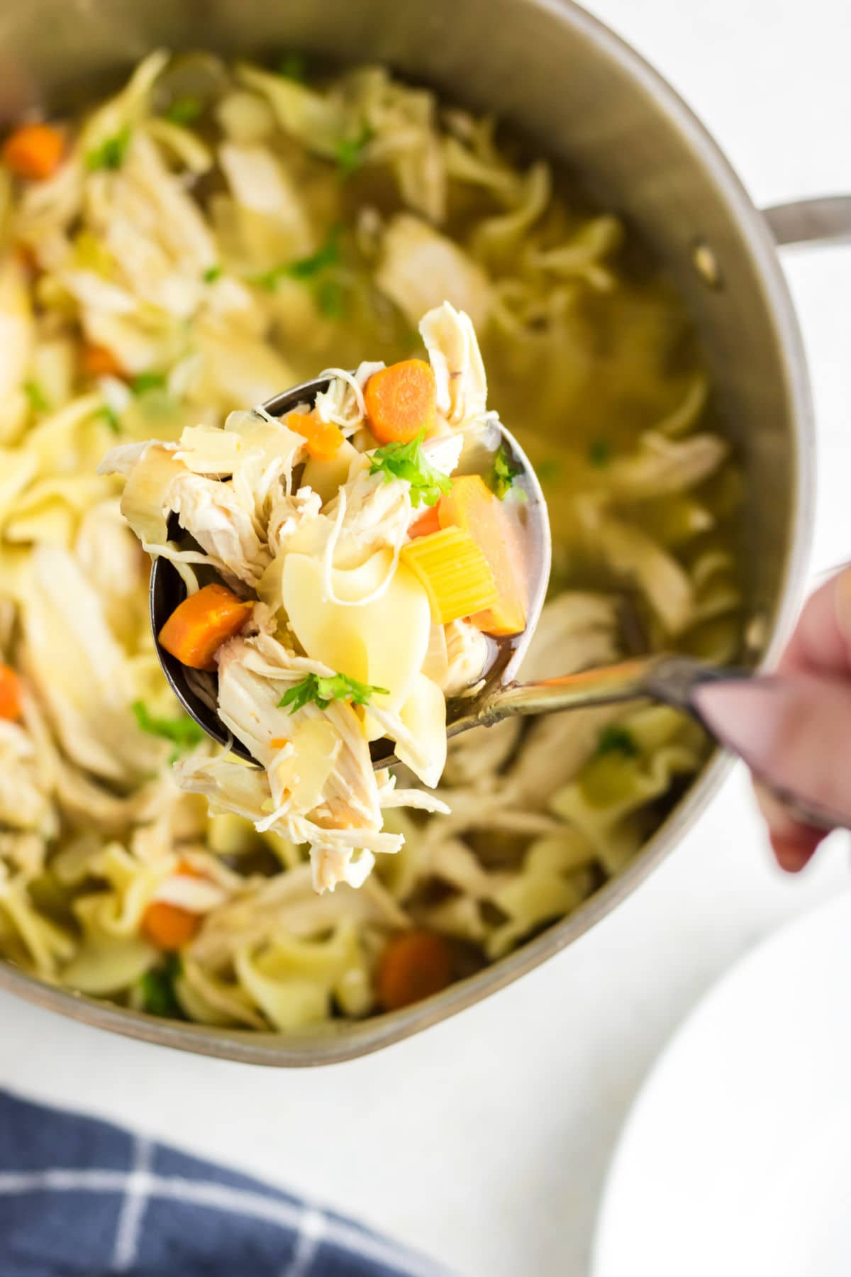 A ladle getting a serving of soup out of a pot.