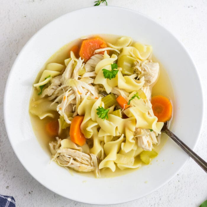 Chicken noodle soup with carrots in a white bowl.