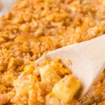 A crunchy topped pineapple casserole with a serving spoon in it.