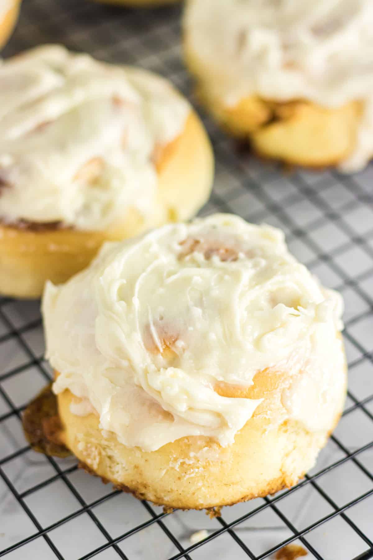Closeup of a finished cinnamon roll with thick, creamy frosting on top.