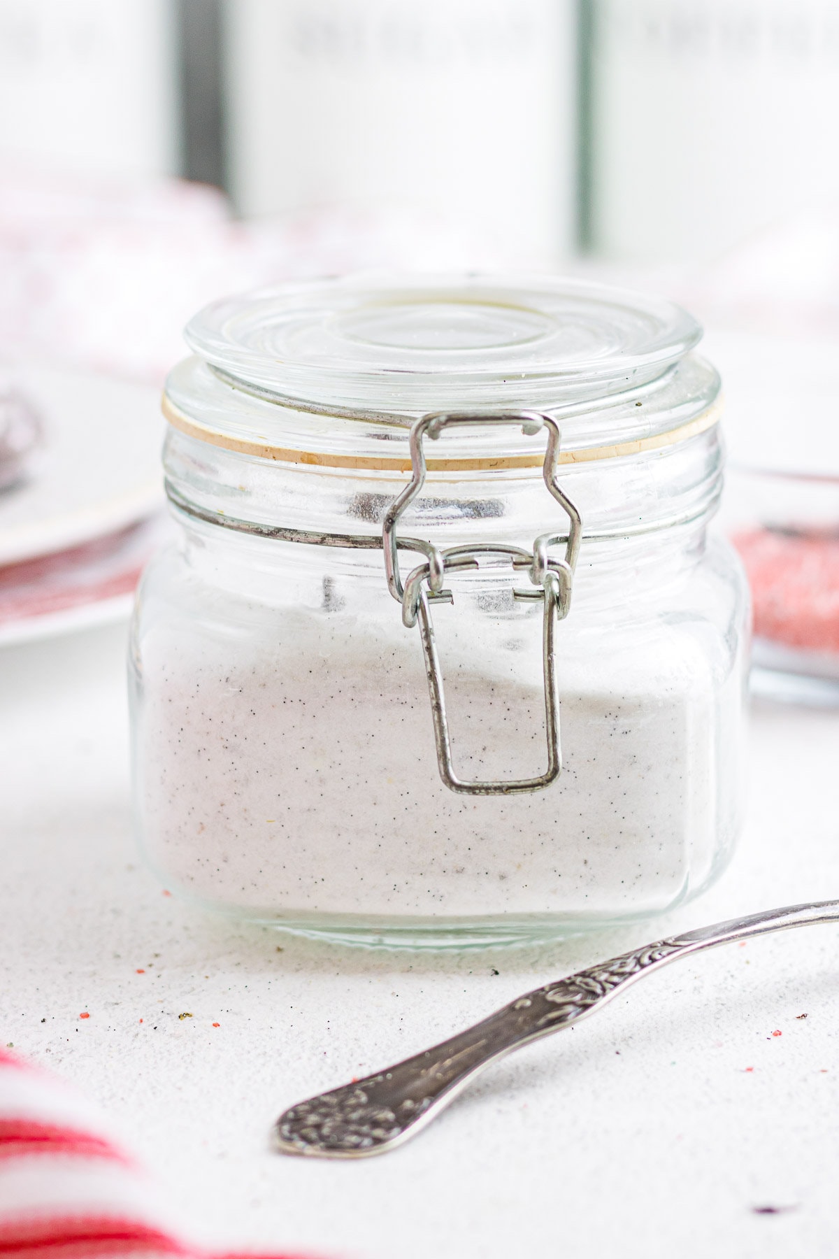 A mason jar filled with vanilla sugar. The black flecks of vanilla bean are visible throughout the white sugar.