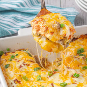 A serving of cheesy breakfast casserole being removed from the pan.