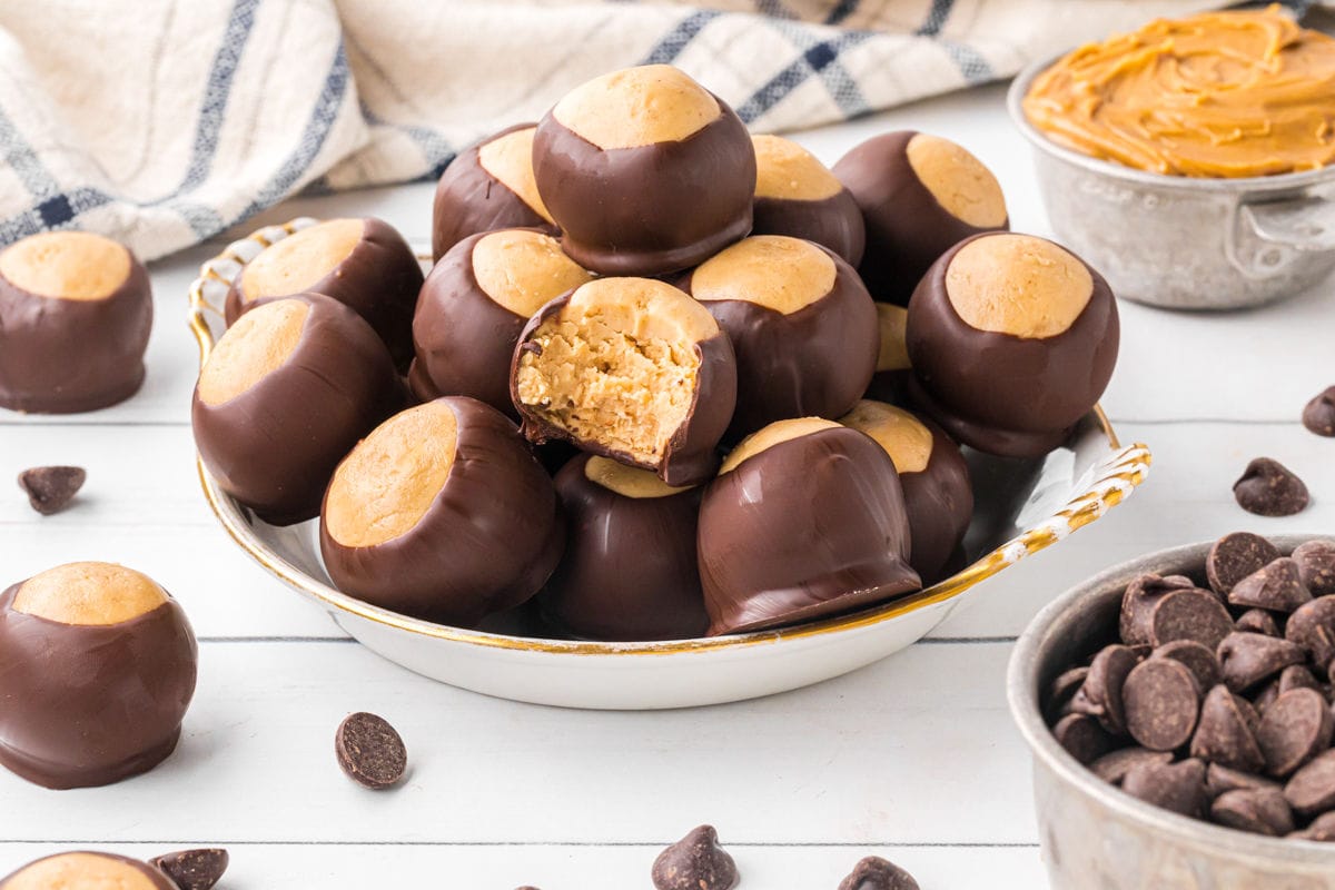 A bowl full of chocolate and peanut butter buckeyes. One has a bite taken out.